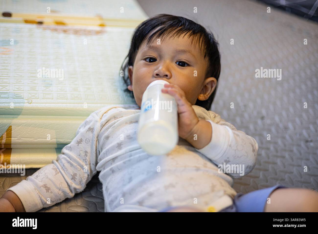 Bimbo che beve latte nella sala giochi, sfondo per pubblicità e carta da parati nella scena dei bambini e dello stile di vita. Foto Stock