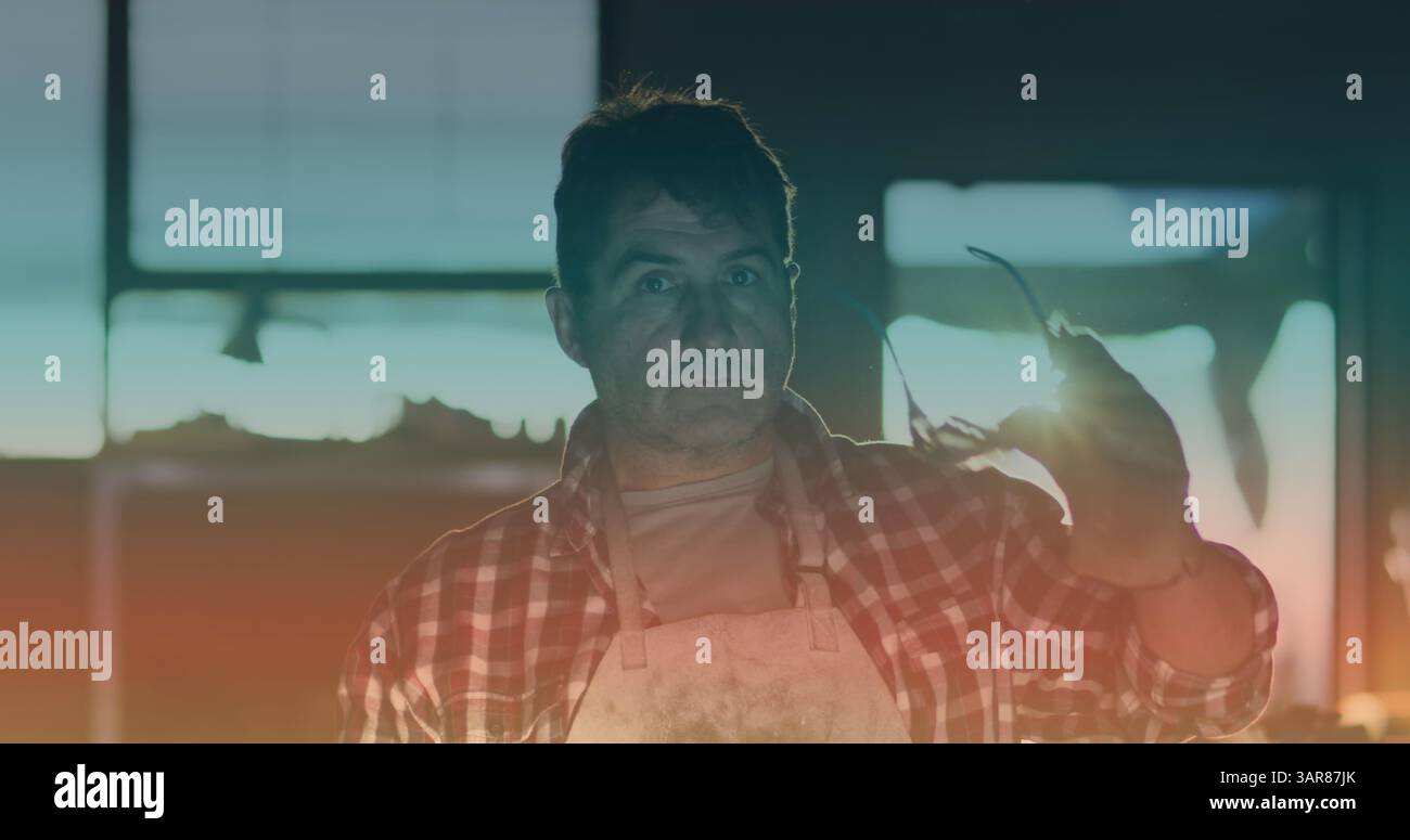 Immagine di uno spot luminoso sul lavoratore maschile caucasico che sorride e indossa occhiali di sicurezza in officina Foto Stock