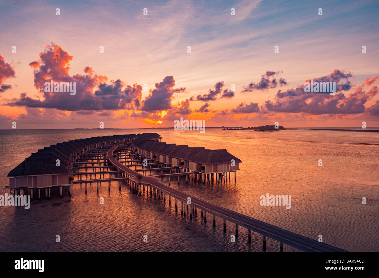 Vista aerea delle splendide ville sull'acqua delle Maldive durante un vibrante tramonto, con acque turchesi, paradiso tropicale e serene vibrazioni dell'isola Foto Stock