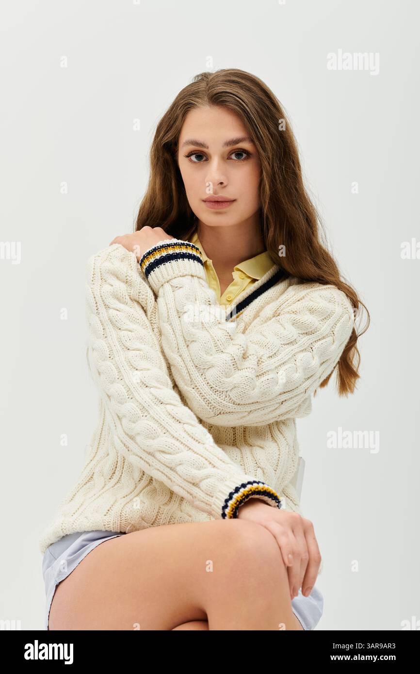 Una giovane donna irradia bellezza e fiducia in un maglione a maglia con un tocco di giallo. Foto Stock