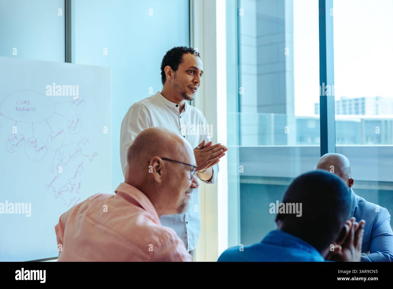 L'immagine raffigura un CEO che facilita una riunione di lavoro in una sala riunioni contemporanea. La scena mette in evidenza leadership, lavoro di squadra e plann strategico Foto Stock