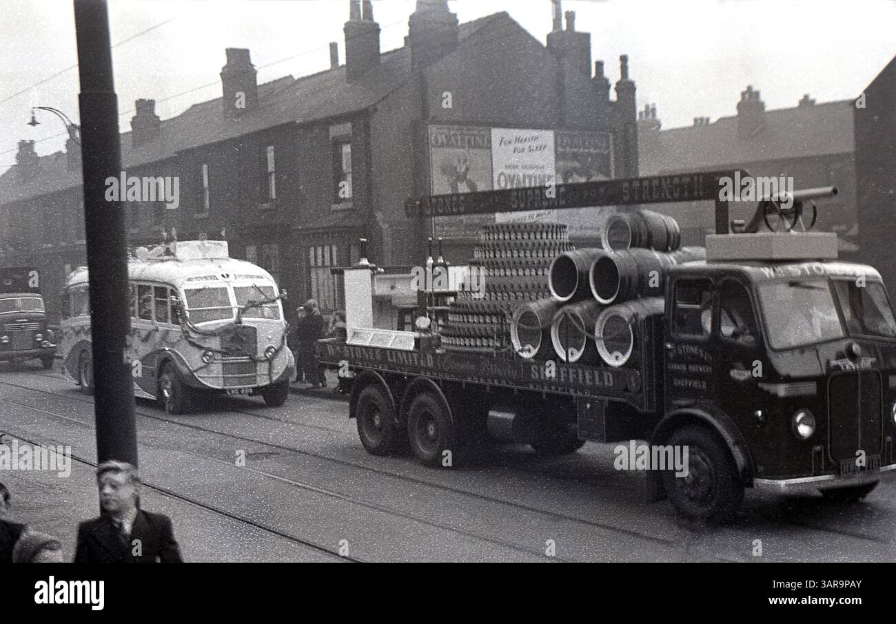 1950, storico carnevale di strada, a Stones of Sheffield, camion aperto sul retro con pile di bottiglie di birra e botti di birra, viaggiando lungo Staniforth Road, Sheffield, Inghilterra, Regno Unito. Sulla parete laterale di una casa a schiera, un poster che promuove la bevanda al malto Ovaltine, lo strapline... Per la salute, per il sonno." Foto Stock