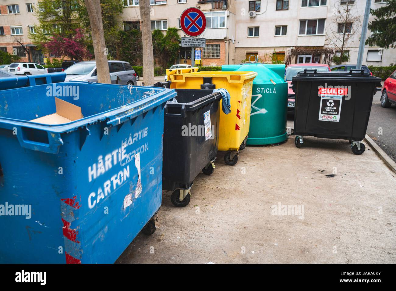 Deva, Romania - 11 aprile 2025 spazio destinato al riciclaggio di contenitori per rifiuti domestici, codici colore, vetro, carta, rifiuti organici Foto Stock