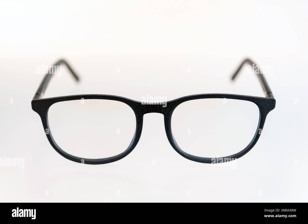 Gli eleganti occhiali da vista neri si trovano su uno sfondo bianco e pulito e presentano un design semplice e moderno Foto Stock