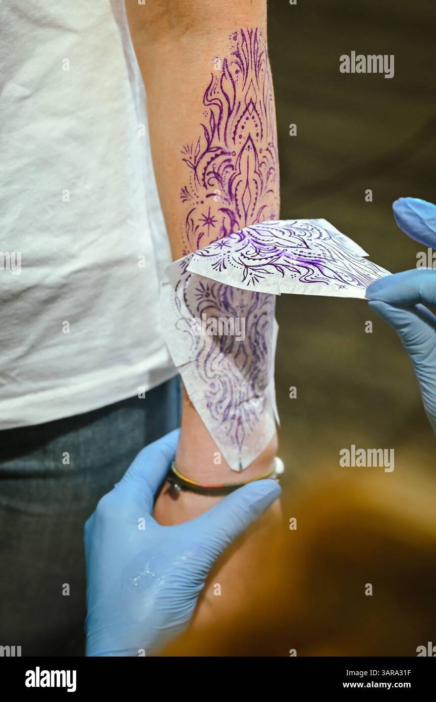Tatuatore che prepara la pelle con lo stencil per un design a inchiostro complesso Foto Stock