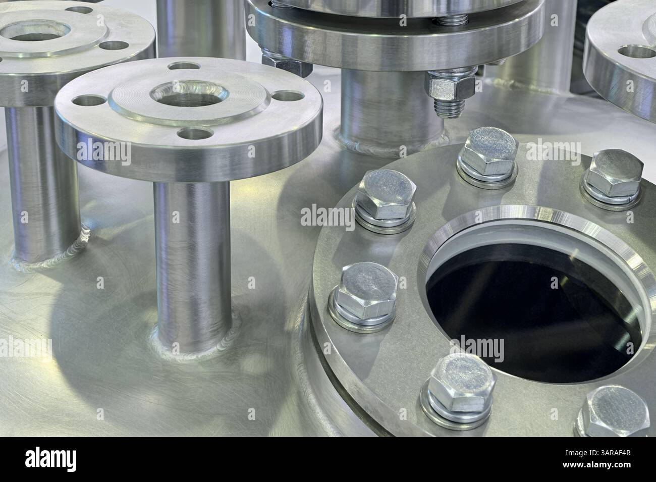 Varie parti di apparecchiature ad alta pressione: Tubi in acciaio inox, flange e tappi, primo piano, background industriale astratto Foto Stock