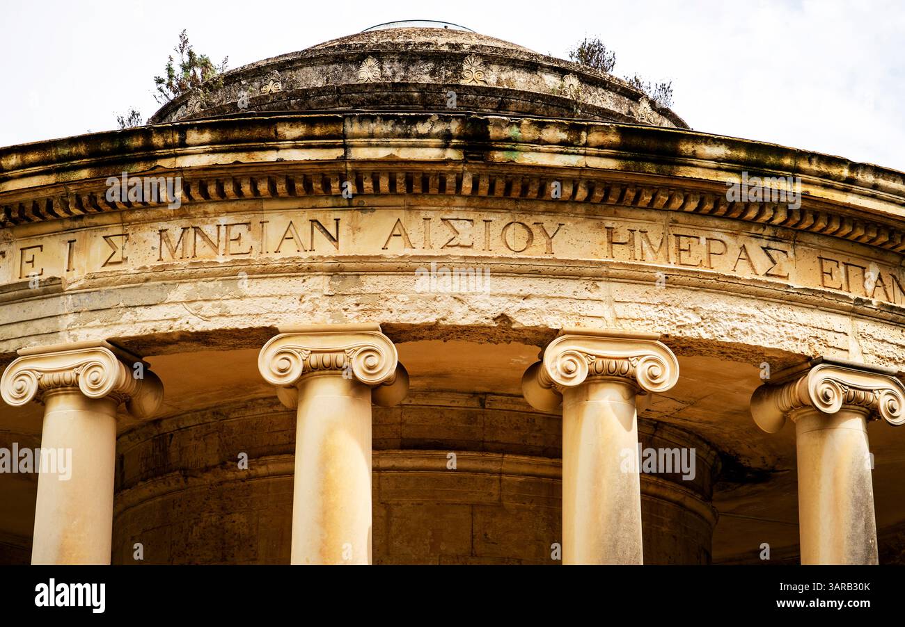 Vista ravvicinata di antiche colonne in pietra e di una struttura circolare con iscrizioni greche, che mostra l'architettura classica e il significato storico Foto Stock