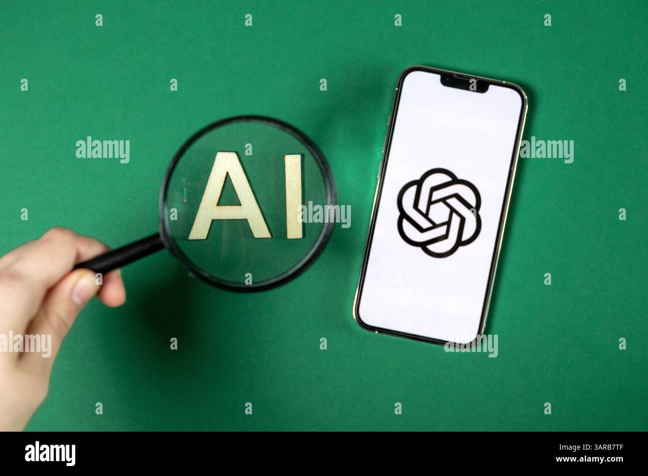 Poznan, Polonia – 14 aprile 2025: Primo piano di una lente di ingrandimento con la mano sopra le lettere ai accanto allo smartphone che mostra il logo ChatGPT, che rappresenta la ricerca e lo Foto Stock