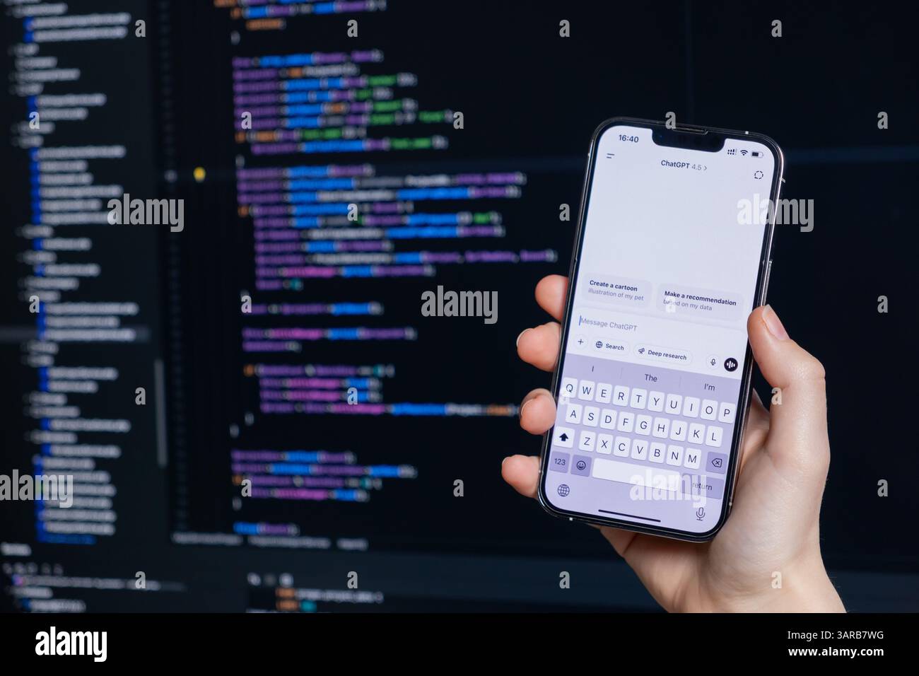 Poznan, Polonia – 14 aprile 2025: Persona con smartphone in mano con ChatGPT 4,5 aperta durante la codifica su un computer, che mostra l'integrazione degli strumenti di intelligenza artificiale i Foto Stock