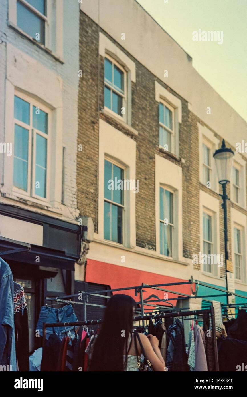 Una giovane donna irriconoscibile che fa shopping al negozio di abbigliamento di seconda mano al mercato di Portobello a Londra Foto Stock