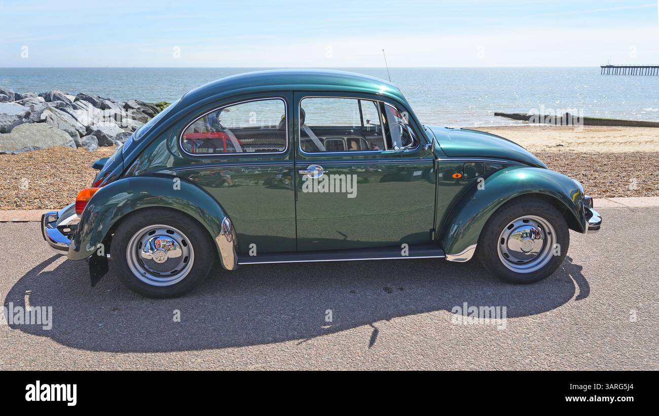 Classic Green Volkswagen 1200 Beetle parcheggiato sulla spiaggia di fronte al mare e sul mare sullo sfondo. Foto Stock