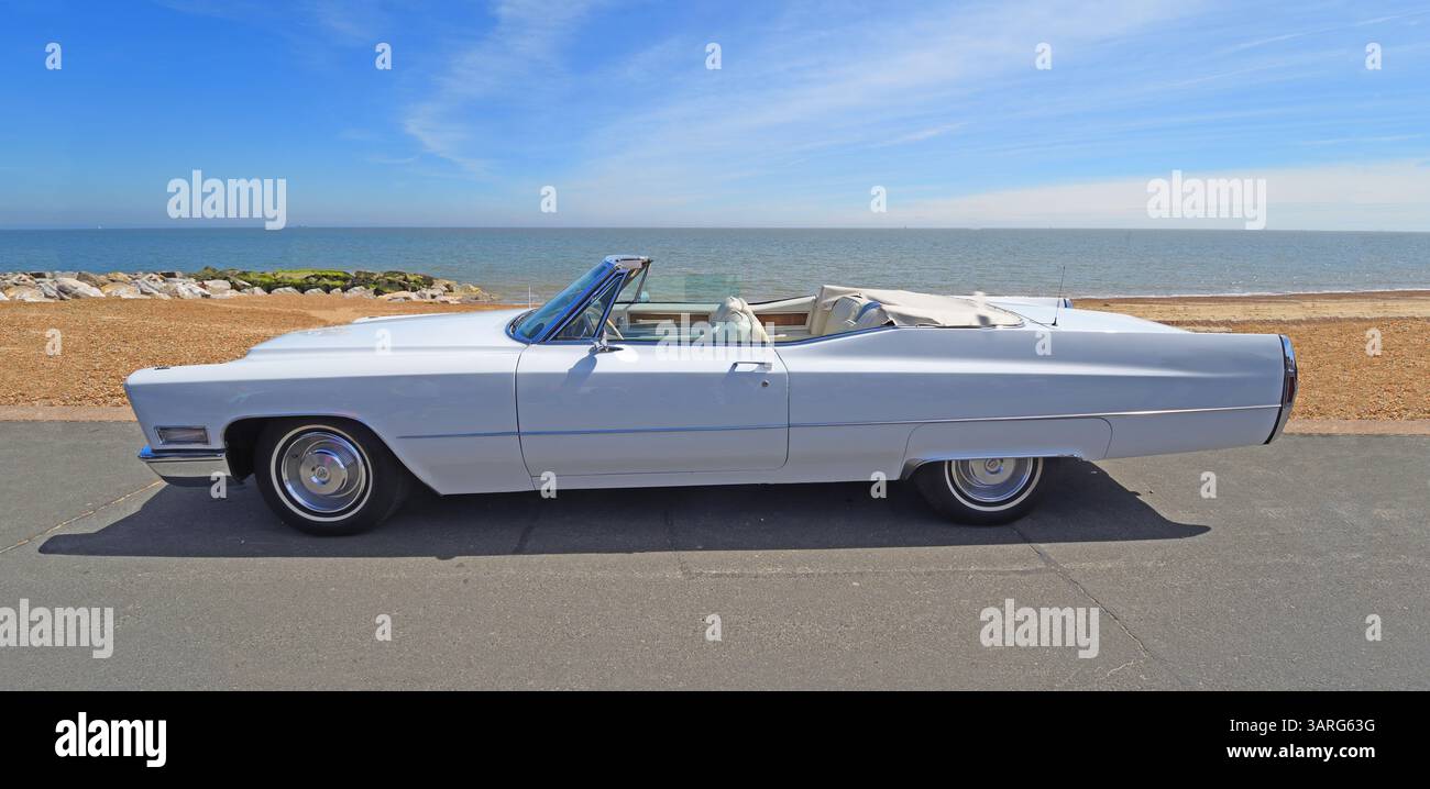Cadillac De Ville Cabriolet bianco classico parcheggiato sulla spiaggia di fronte al mare e sul mare sullo sfondo Foto Stock