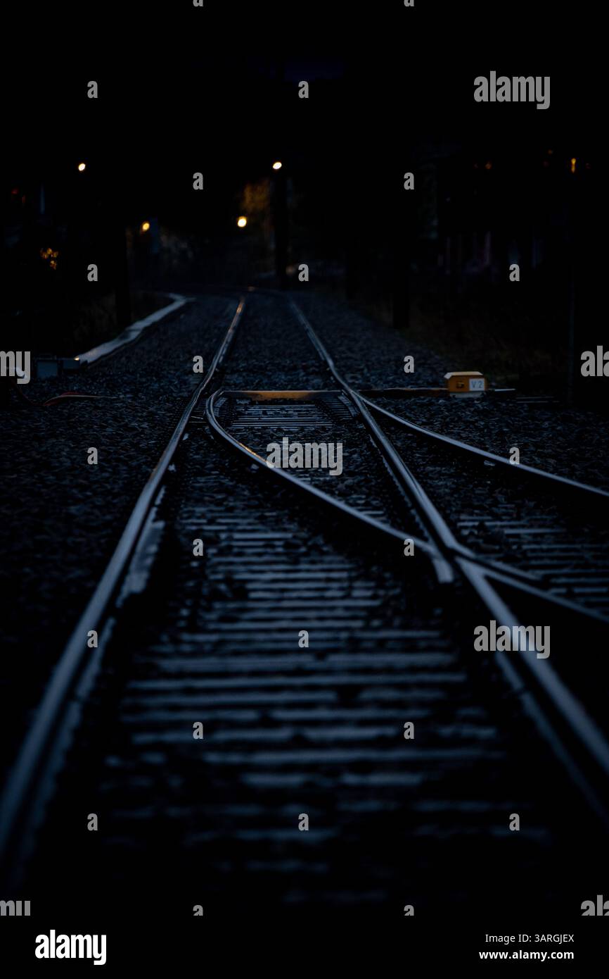 Una notte piovosa alla stazione ferroviaria con riflessi che catturano le luci Foto Stock