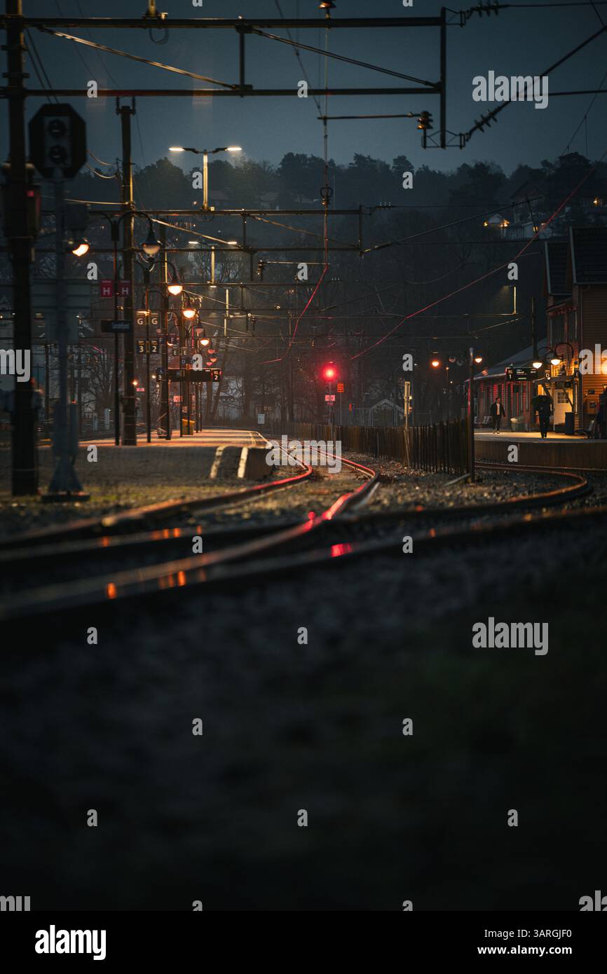 Una notte piovosa alla stazione ferroviaria con riflessi che catturano le luci Foto Stock