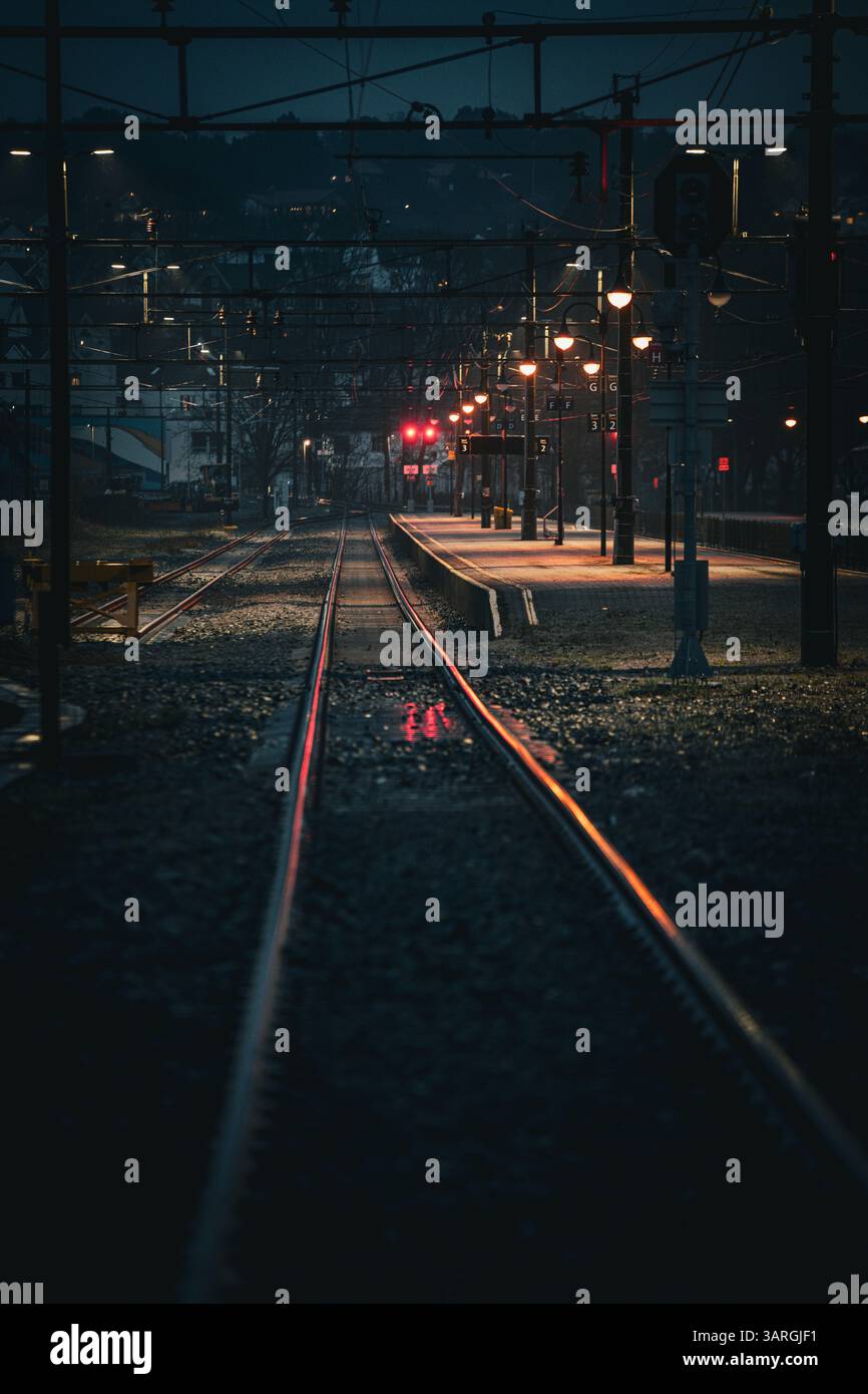 Una notte piovosa alla stazione ferroviaria con riflessi che catturano le luci Foto Stock