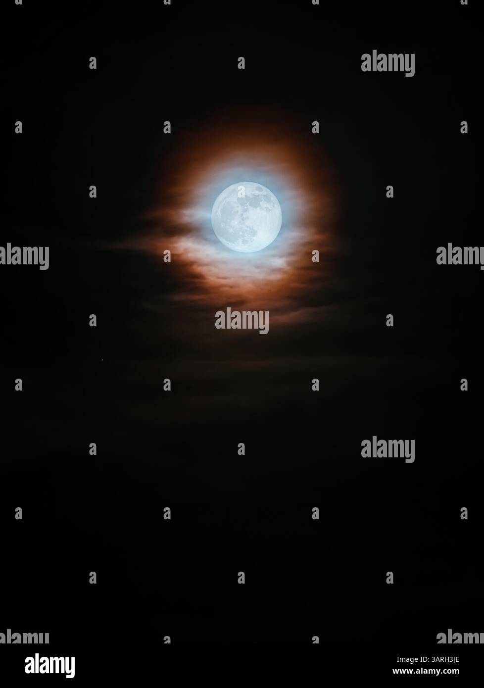 Luna piena mistica che si illumina nel cielo notturno, circondata da nuvole sottili e un alone colorato. Una scena cinematografica drammatica che evoca mistero, la natura Foto Stock