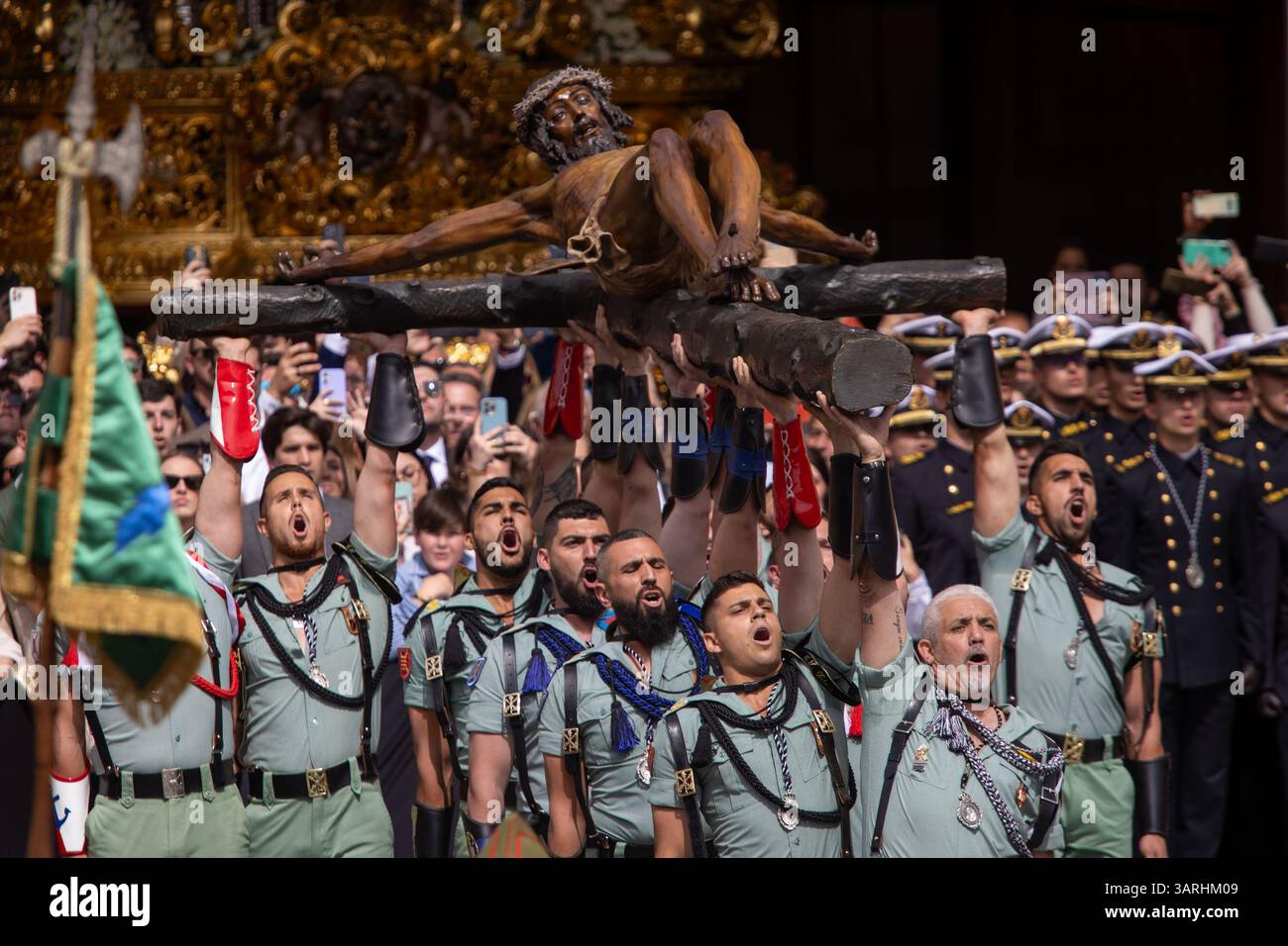 Un gruppo di legionari trasporta il Cristo di Mena durante il trasferimento del Cristo di Mena il giovedì Santo, una delle processioni della settimana Santa più famose di tutta la Spagna, sia per ciò che rappresenta sia per la partecipazione della Legione che canta "El Novio de la Muerte", un canto emblematico diventato l'inno non ufficiale della Legione spagnola. Foto Stock