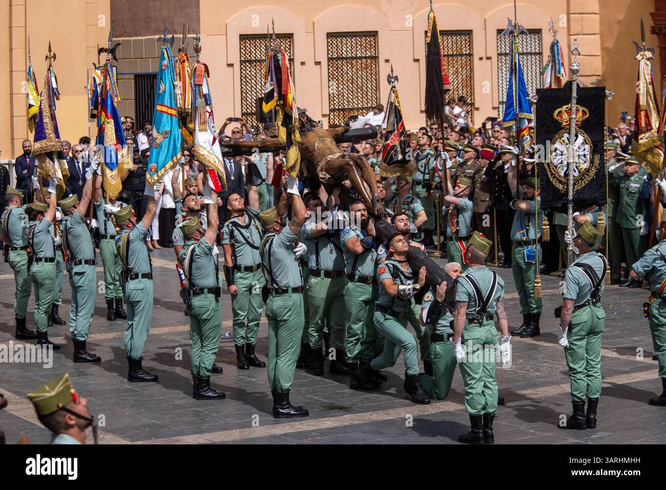 Un gruppo di legionari trasporta il Cristo di Mena durante il trasferimento del Cristo di Mena il giovedì Santo, una delle processioni della settimana Santa più famose di tutta la Spagna, sia per ciò che rappresenta sia per la partecipazione della Legione che canta "El Novio de la Muerte", un canto emblematico diventato l'inno non ufficiale della Legione spagnola. Foto Stock