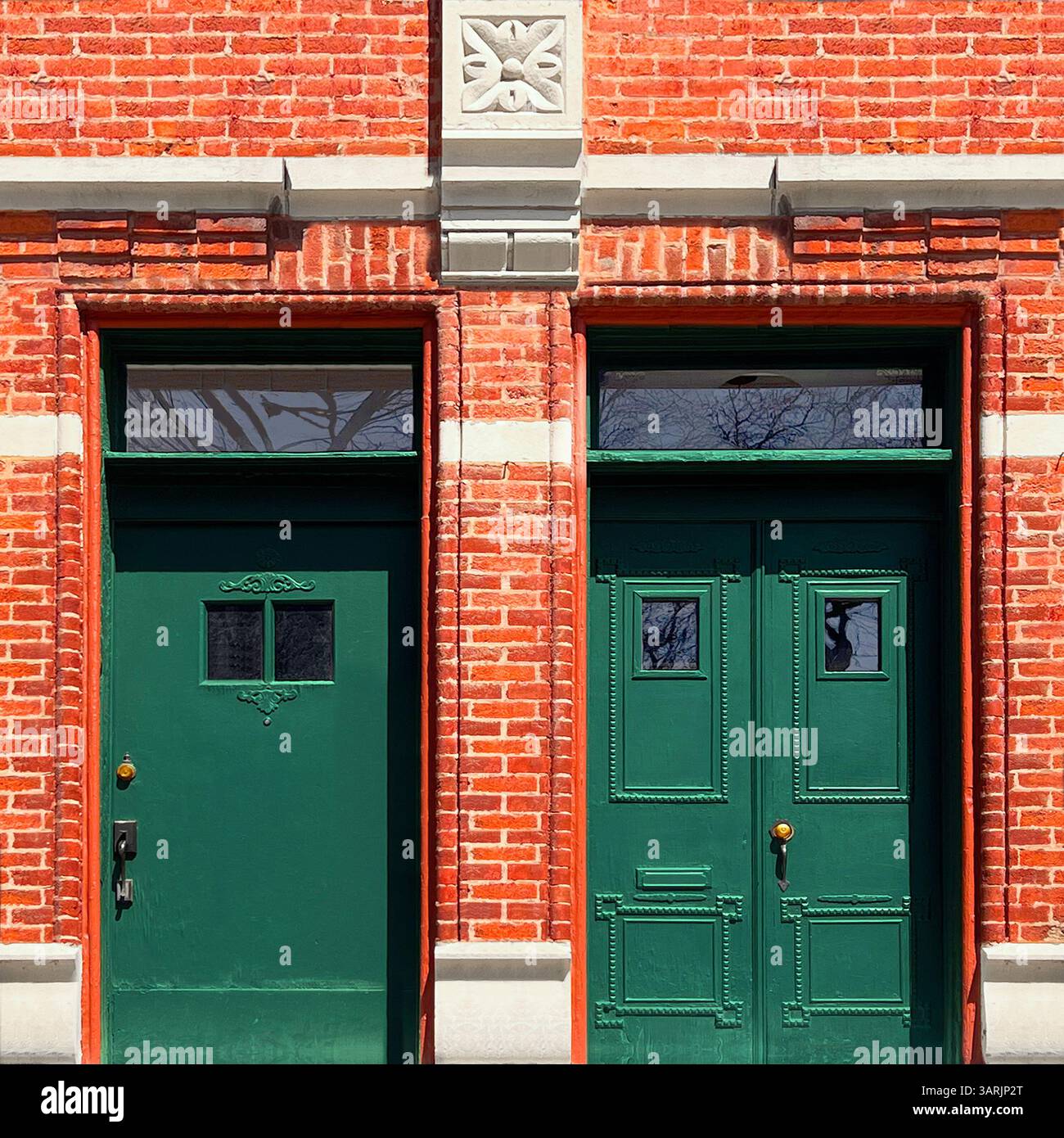 Due porte di colore verde scuro con finestre sullo specchio di poppa e finiture ornamentali adagiate in un'audace facciata in mattoni rossi a Chicago - Immagine stock catturata con smartphone