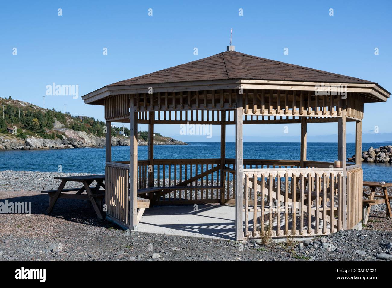 Un grande gazebo in legno a forma di ottagono su una spiaggia che si affaccia sull'oceano. Il tetto è coperto da tegole marroni. I lati sono realizzati con trattamento a pressione Foto Stock Un grande gazebo in legno a forma di ottagono su una spiaggia che si affaccia sull'oceano. Il tetto è coperto da tegole marroni. I lati sono realizzati con trattamento a pressione Foto Stock