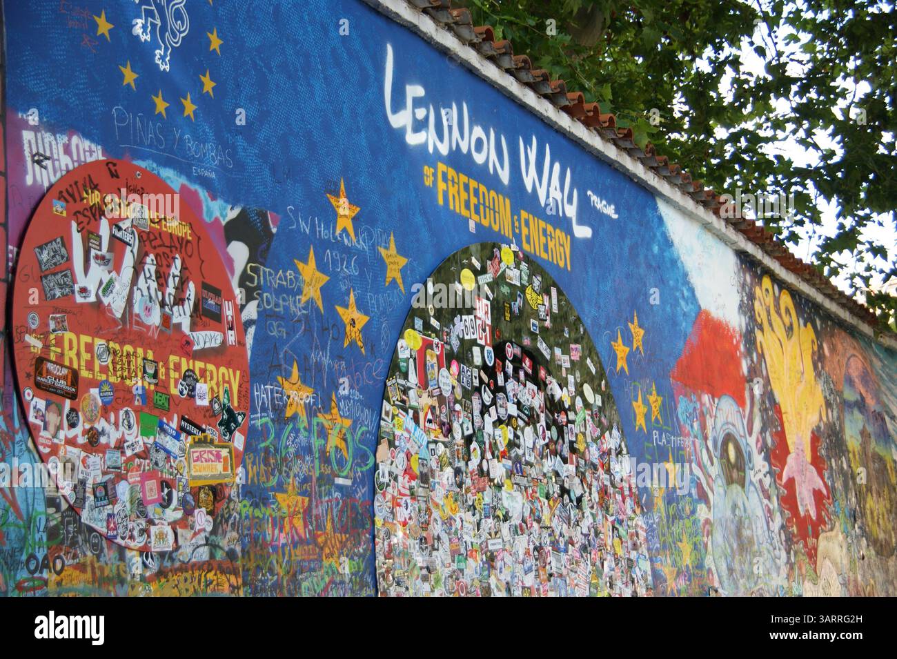 Il colorato e in continua evoluzione muro Lennon a Praga, Repubblica Ceca, ricoperto di strati di graffiti ispirati a John Lennon, simboli di pace e messaggi. Foto Stock