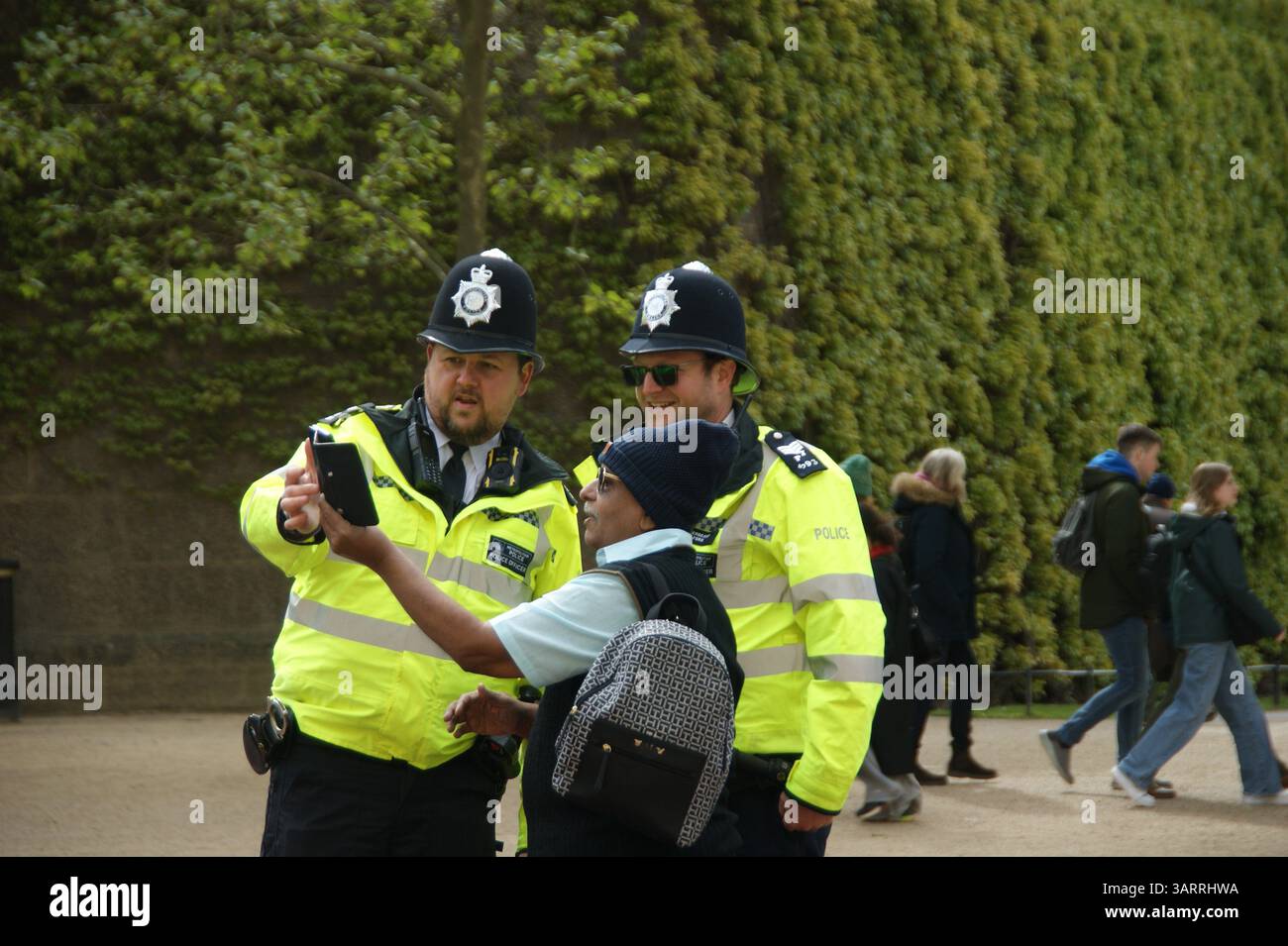 Due agenti di polizia in uniforme nel Regno Unito si fermano per un selfie con un membro del pubblico. Gli ufficiali, con il loro distintivo custode Foto Stock