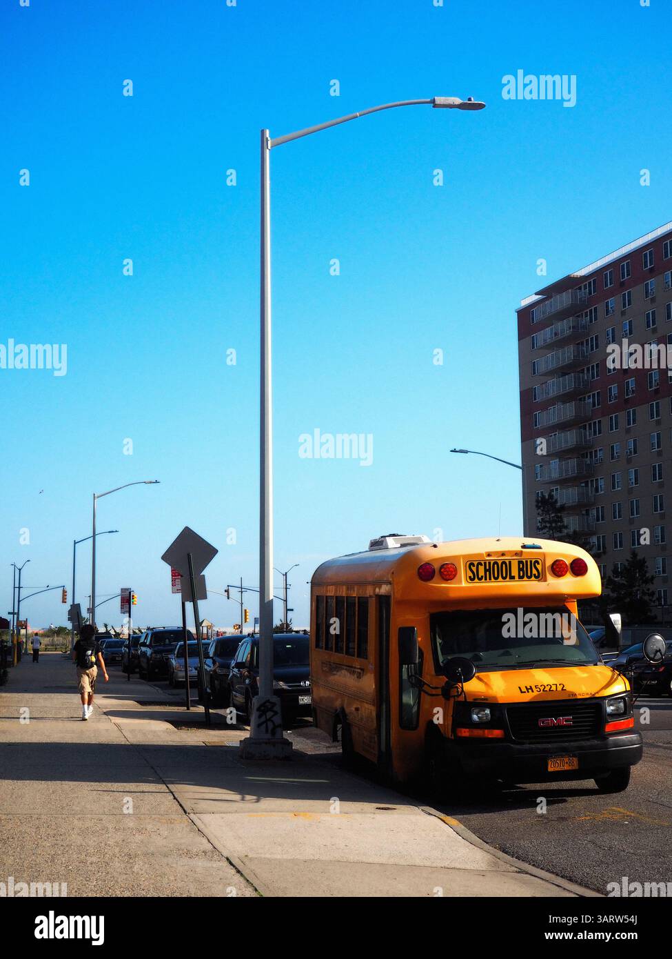 Scuolabus giallo sotto un cielo estivo luminoso a far Rockaway, New York Foto Stock
