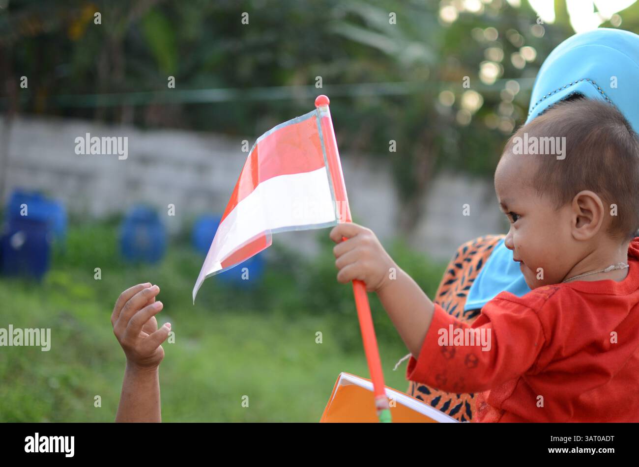 09 luglio 2013 - Sidoarjo, Giava orientale, Indonesia - Un bambino che porta una replica della bandiera indonesiana nel campo profughi sciita di Sidoarjo. Un totale di 93 bambini, di età compresa tra i 6 e i 18 anni, sono fuggiti dalla violenza sciita. Il governo provinciale di Giava orientale vieta ai bambini rifugiati sciiti di frequentare la scuola fuori dai campi. Questo Ramadan segna un anno dall'espulsione della comunità sciita a Sampang. Hanno spostato due campi profughi, ma fino a questo momento non ci sono segni di sciiti - Sampang ha permesso di tornare a casa. (Immagine di credito: © Arief Priyono/ZUMAPRESS.com) Foto Stock