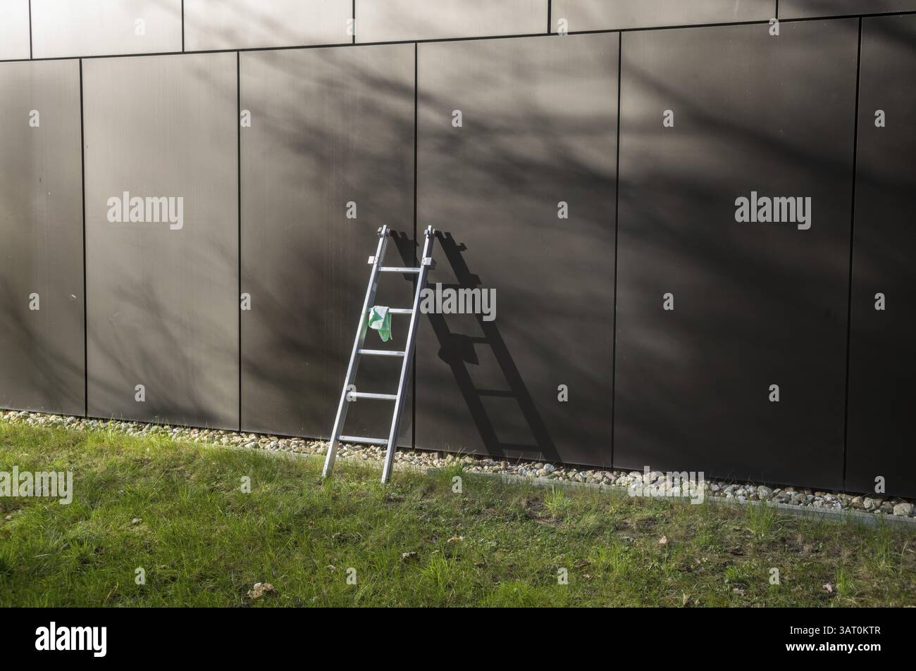 Le attrezzature dell'equipaggio per le pulizie sono lasciate sul prato di prato di fronte alla facciata dell'edificio dall'architettura moderna durante il giorno Foto Stock