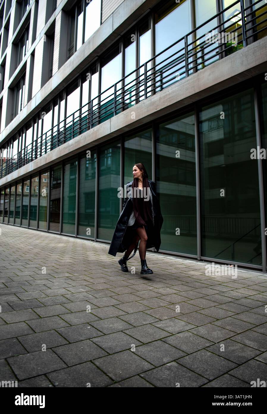 Elegante donna che corre e salta di fronte a un edificio di uffici a Stoccarda, Germania Foto Stock