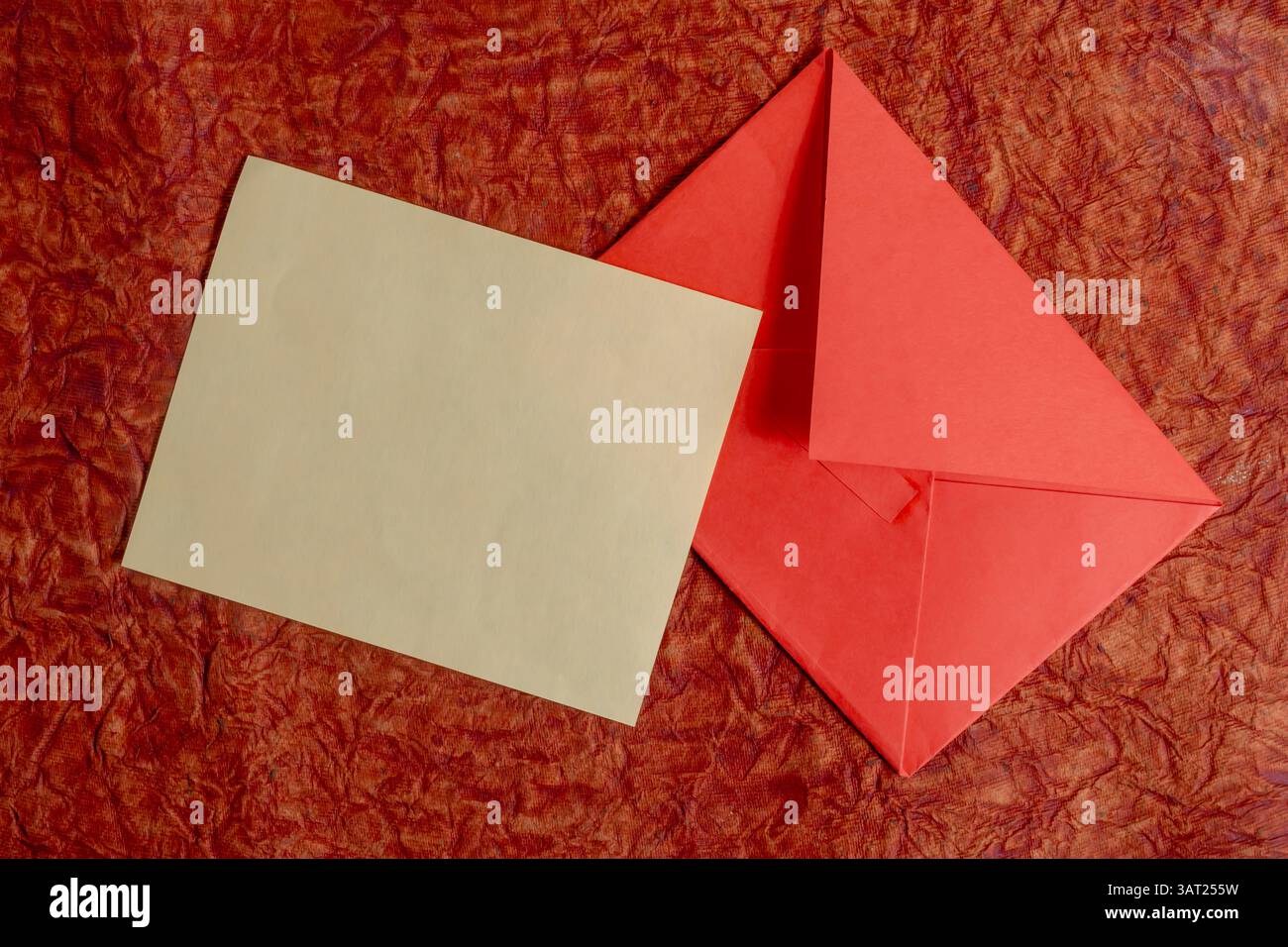 Un design piatto con una carta marrone semplice e una busta rossa vivace su una superficie rossa. Perfetto per concetti quali corrispondenza, donazioni o eventi Foto Stock