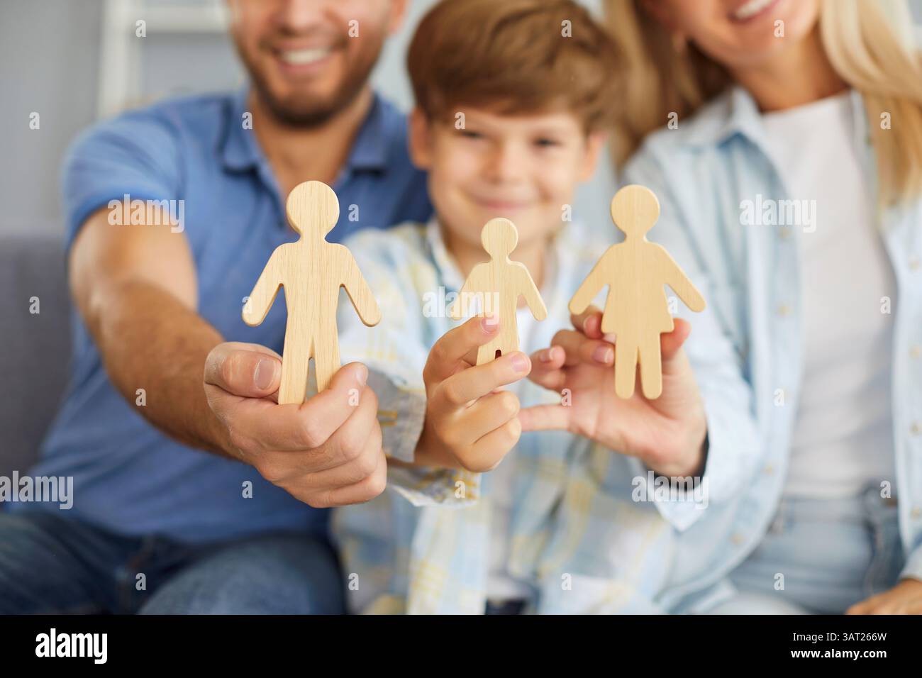 Famiglia felice con bambino che tiene a casa le figure di legno Foto Stock
