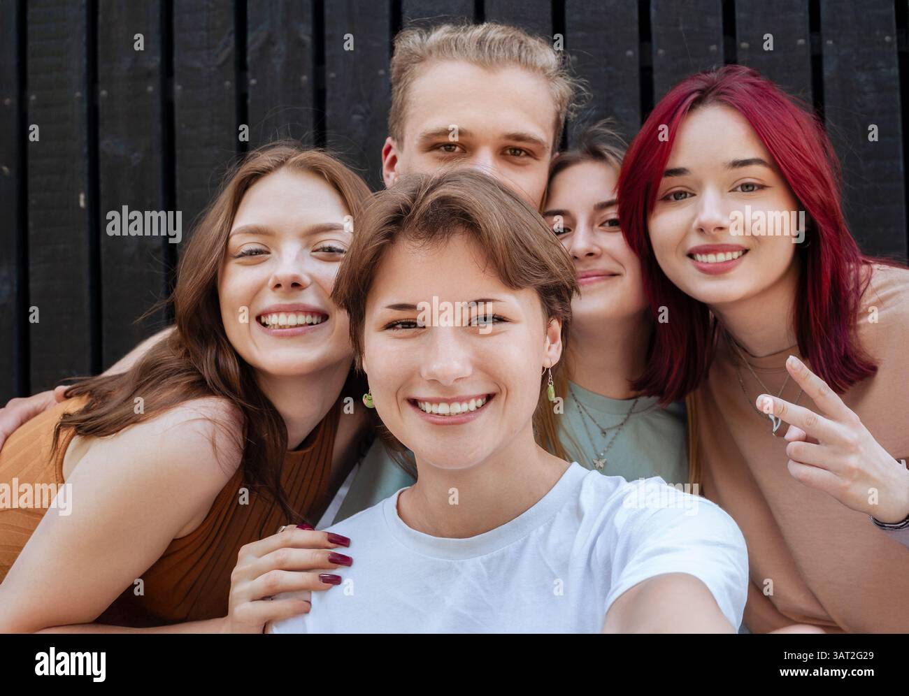 Un gruppo sorridente di giovani amici che fanno un selfie all'aperto Foto Stock