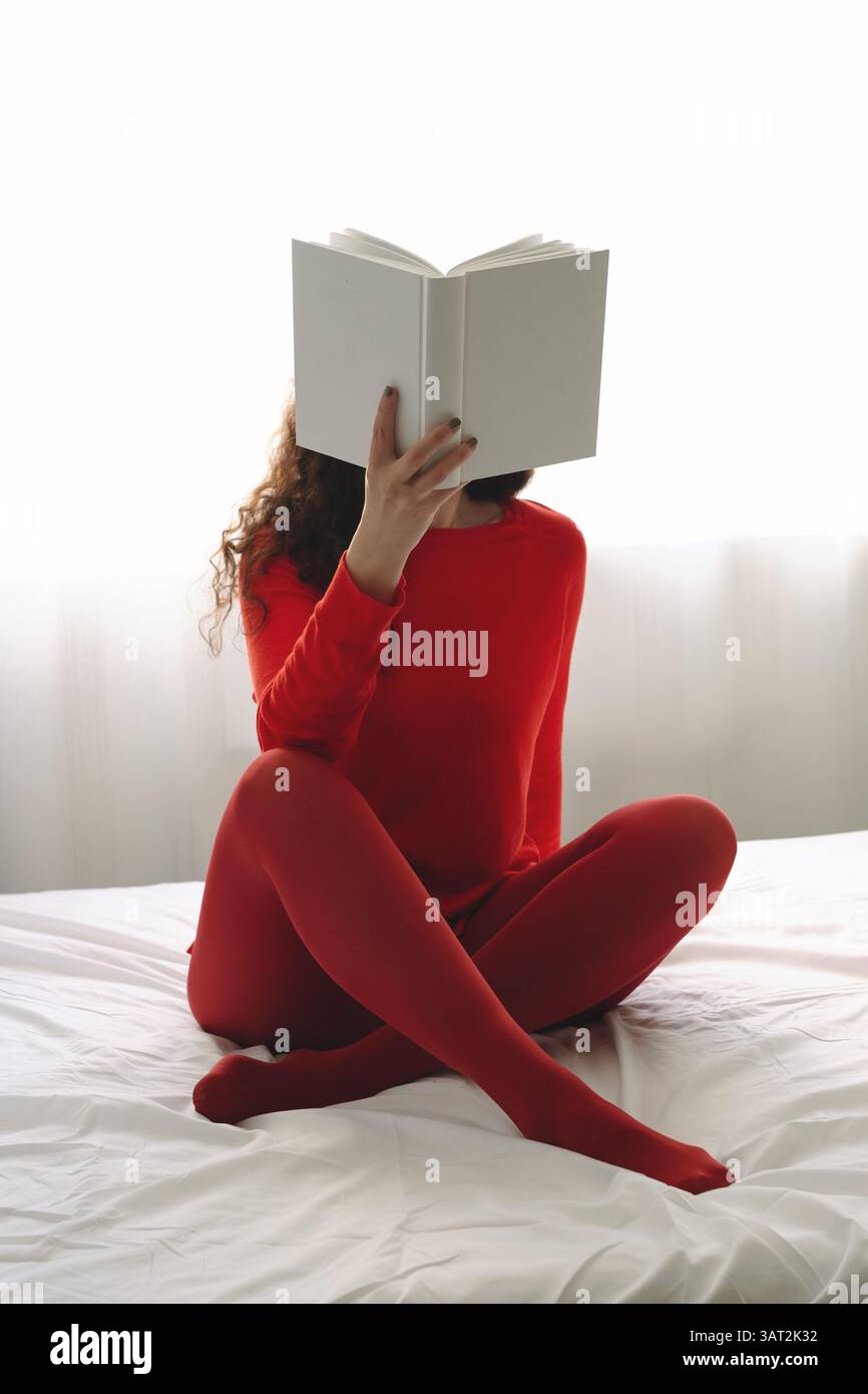 la donna nasconde la faccia con il libro mentre legge Foto Stock