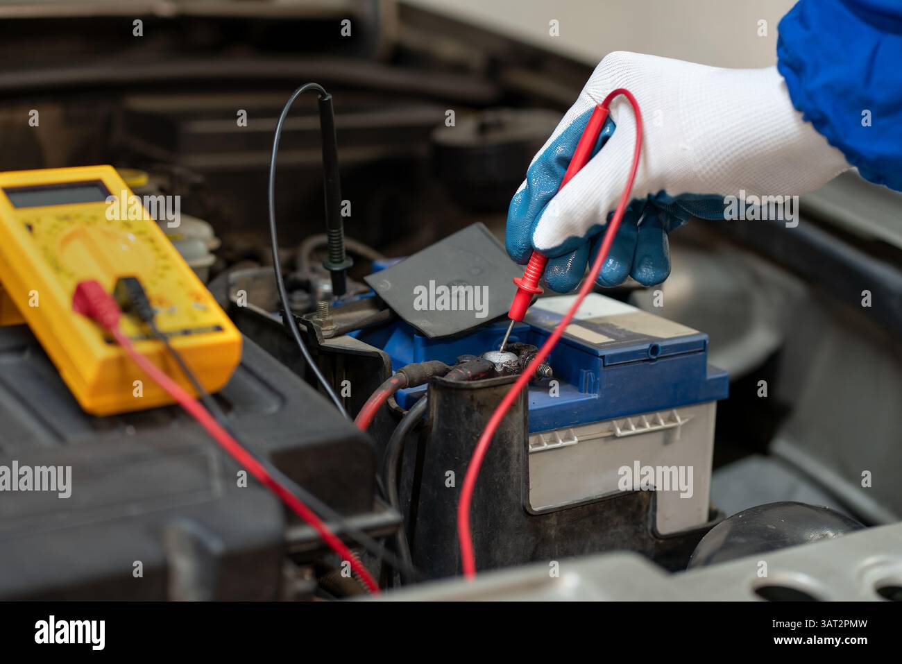 L'ingegnere elettrico utilizza un multimetro per testare l'impianto elettrico e la corrente del motore di un'auto in un'officina automobilistica Foto Stock