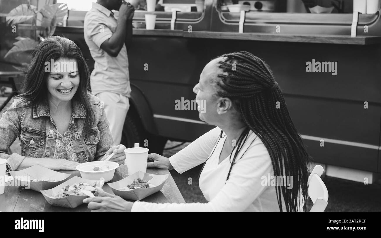 Donne anziane felici che mangiano al ristorante Food Truck all'aperto - stile di vita primaverile e concetto di cena - Focus sul volto femminile caucasico - bianco e nero Foto Stock