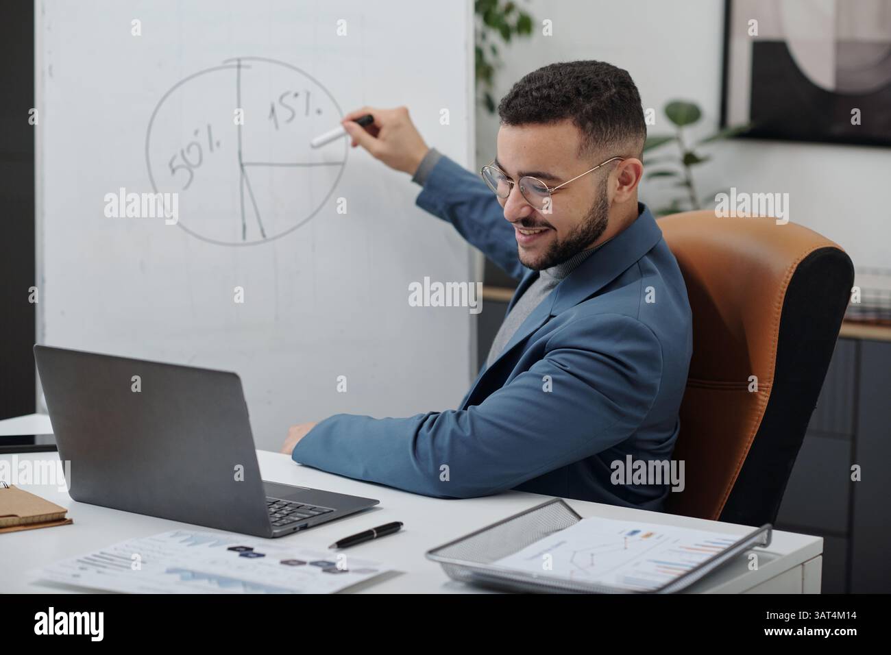 Uomo sorridente del Medio Oriente che presenta in riunione online Foto Stock