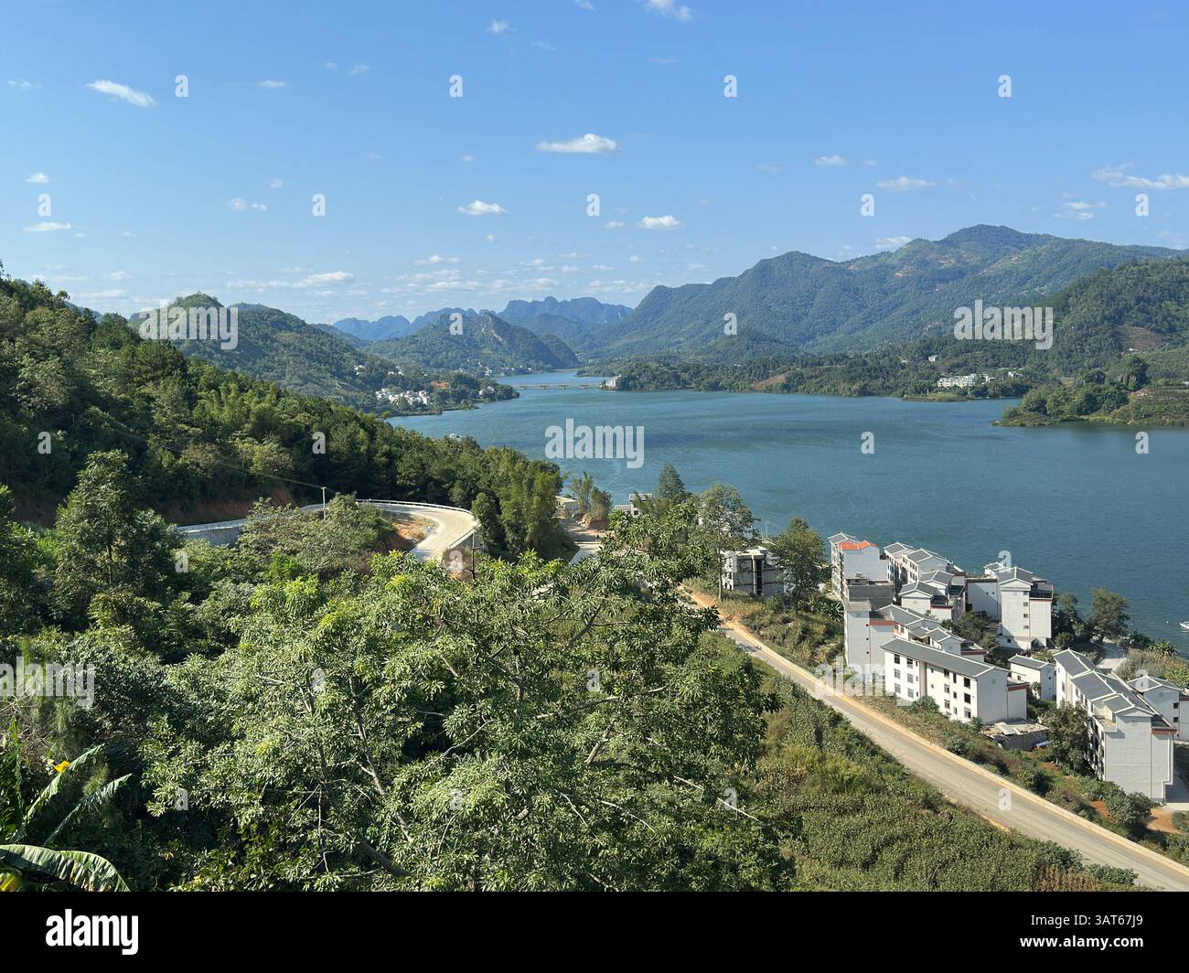 Una vista mozzafiato di un lago con montagne, alberi e un cielo blu. Foto Stock
