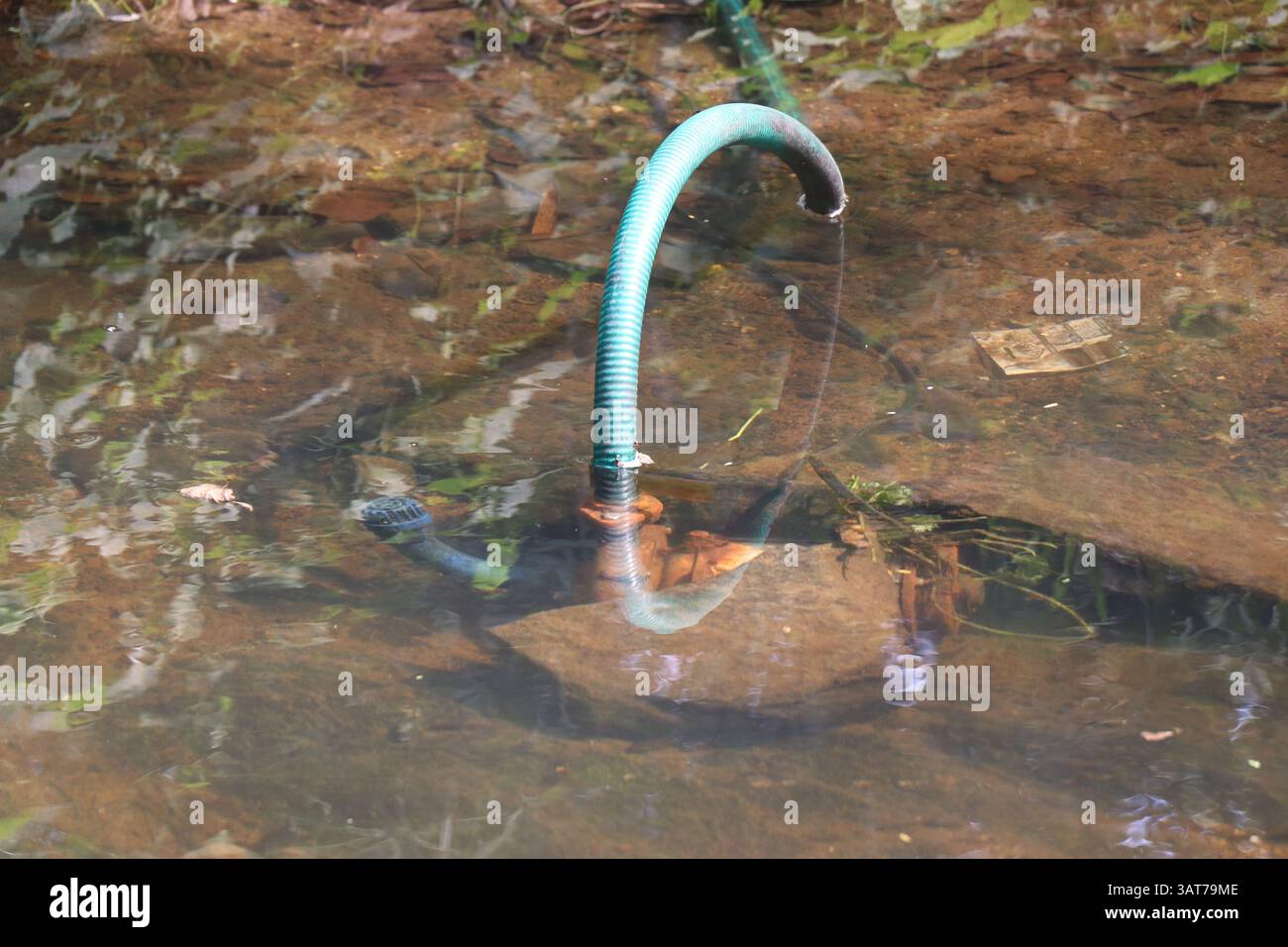 Pompa dell'acqua immergibile su un piccolo laghetto con acqua pulita. Pompa dell'acqua rustica in acqua Foto Stock
