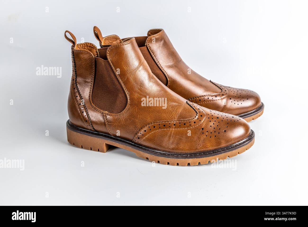 Primo piano di stivali Chelsea in pelle marrone con design a punta alata in brogue e suola robusta. Foto Stock
