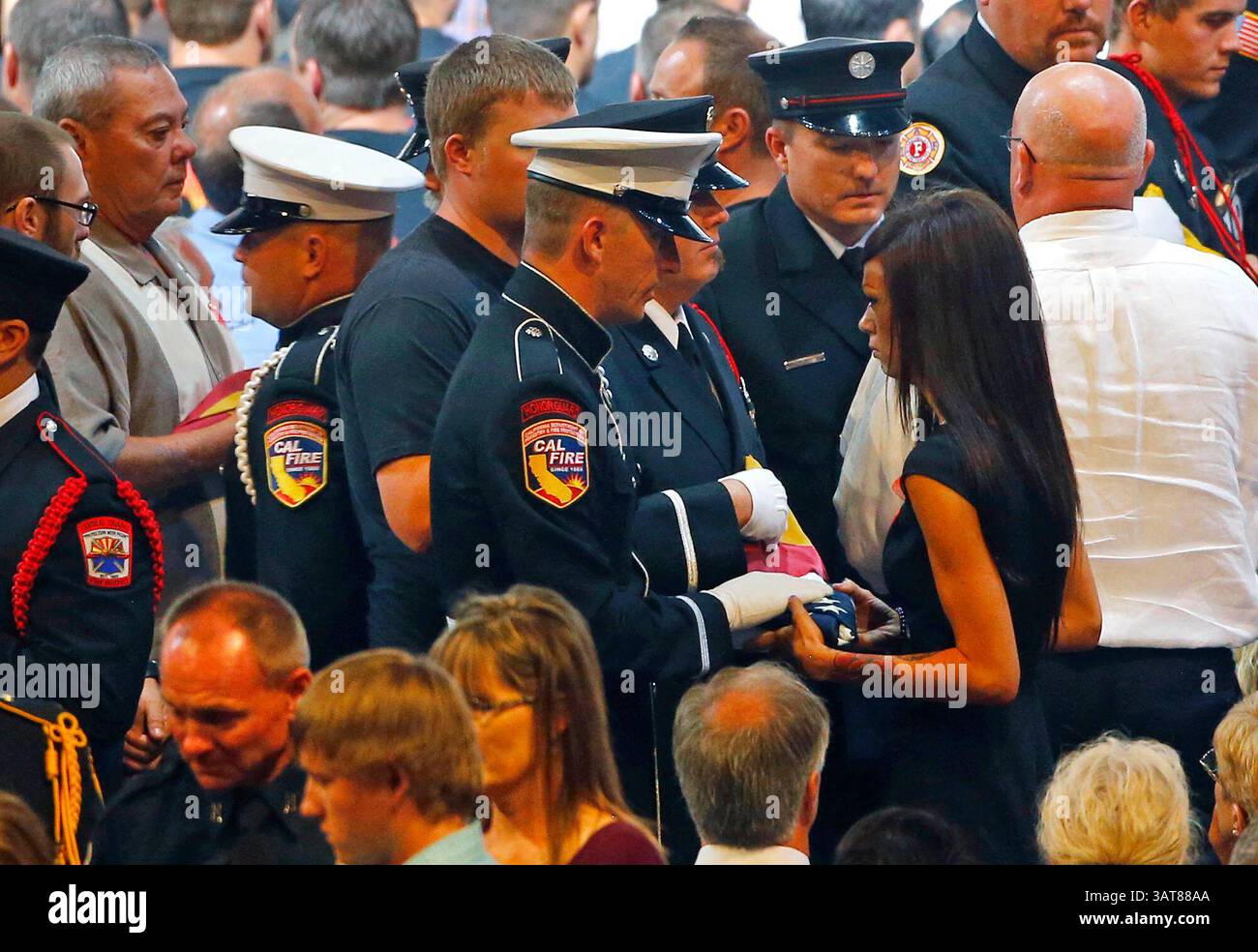 9 luglio 2013 - Prescott Valley, Arizona, Stati Uniti - una guardia d'onore presenta JULIANN ASHCRAFT, moglie del pompiere caduto Andrew Ashcraft con una bandiera americana durante un servizio commemorativo al Tim's Toyota Center per 19 pompieri fuochi di Granite Mountain uccisi il 30 giugno, combattendo contro l'incendio di Yarnell Hill. (Immagine di credito: © David Kadlubowski-POOL/The Arizona Republic/ZUMAPRESS.com) Foto Stock