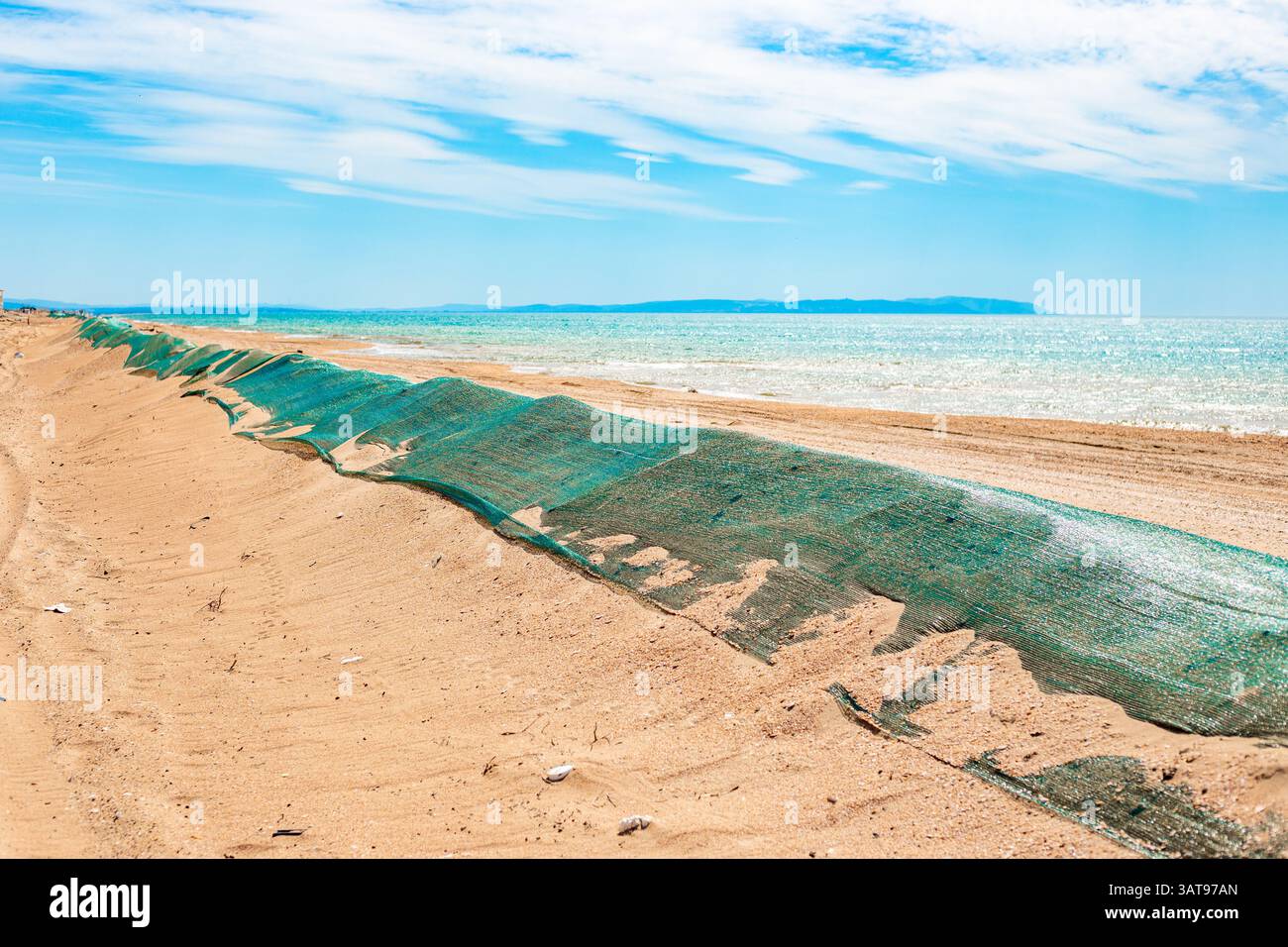 Fuoriuscita di olio combustibile in mare. Duna di sabbia di barriera ricoperta da rete protettiva per impedire che l'olio combustibile venga gettato a terra dalle onde. Disastro ecologico, metodi di elim Foto Stock