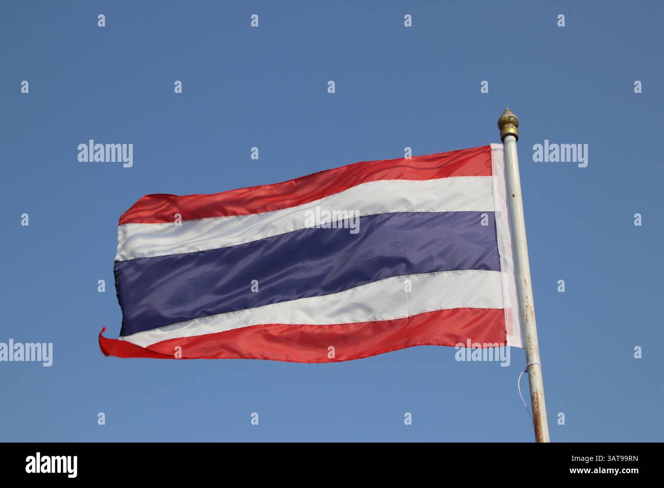 Bandiera thailandese con sfondo blu del cielo. Bandiera che sventola nel vento. Foto Stock