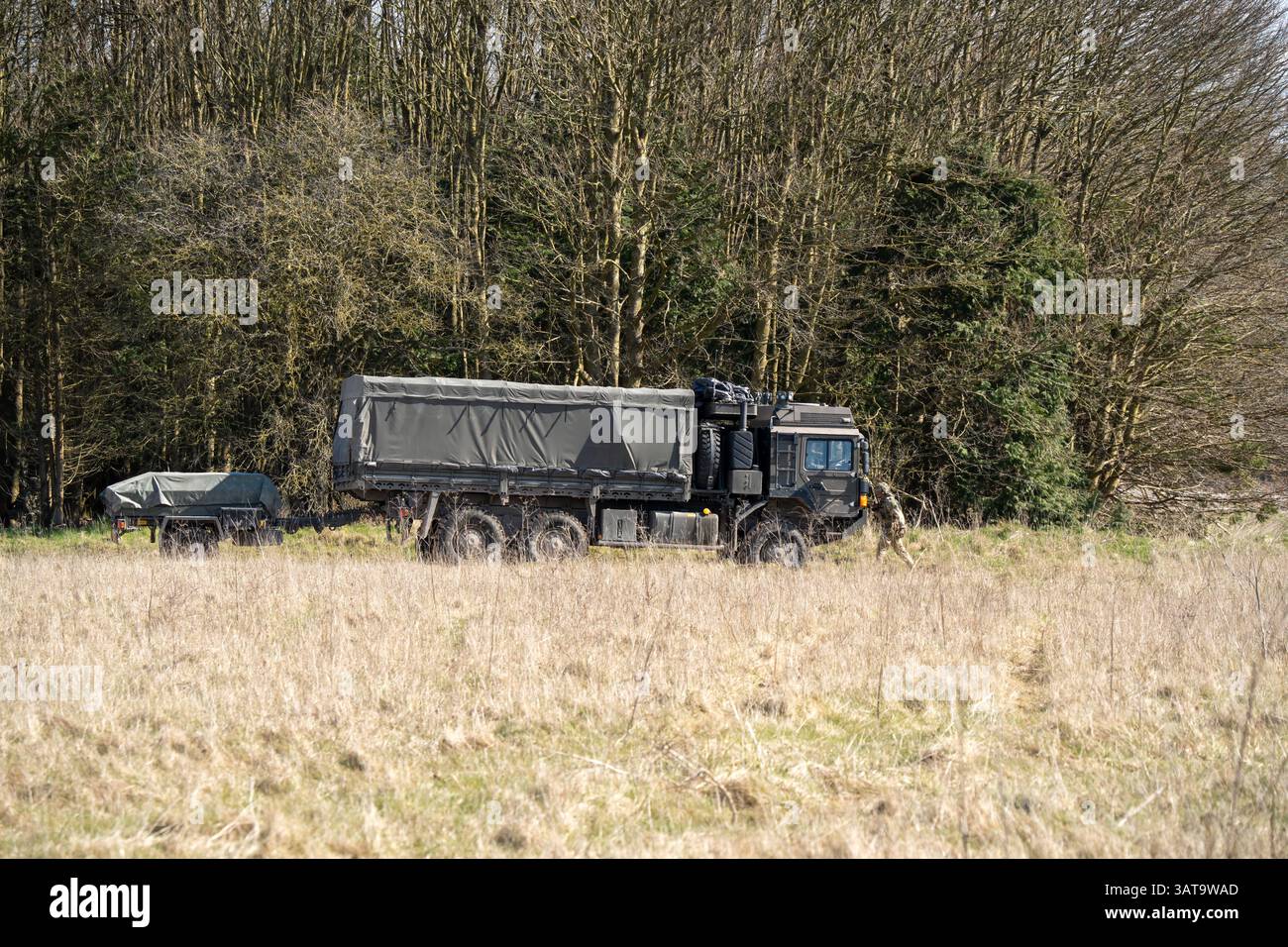 Camion multiuso MAN HX 6x6 dell'esercito britannico con rimorchio in movimento lungo una pista sterrata in campagna Foto Stock