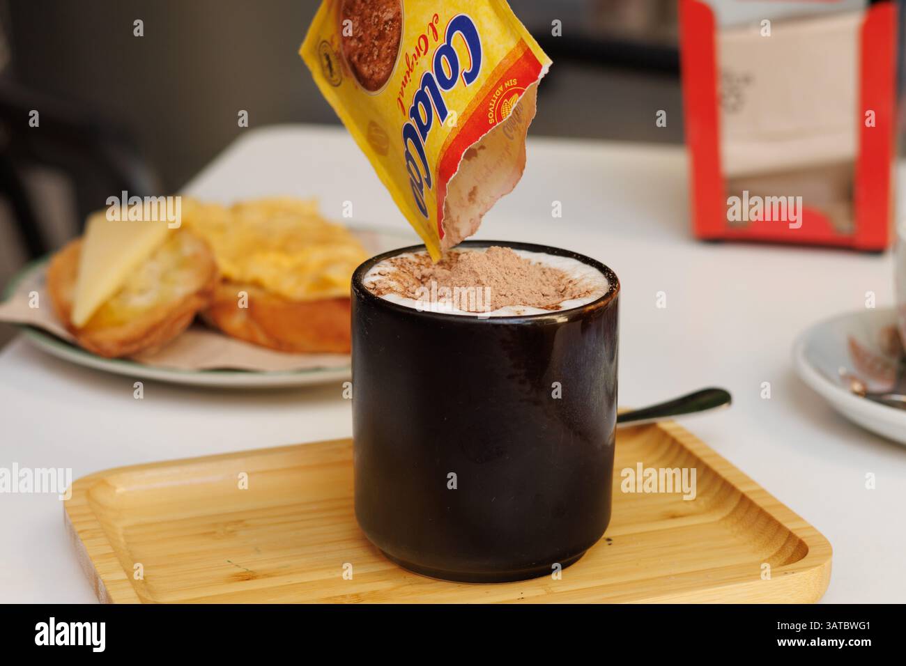 Preparate una colazione confortante, versate Cola Cao nel latte caldo Foto Stock