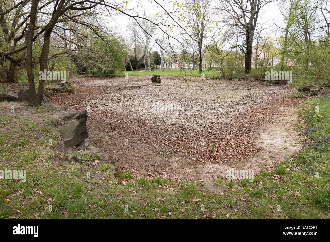 Laghetto vuoto in un parco pubblico di Dresda, Germania. Nel 2025 non c'è acqua durante la stagione primaverile. Il fondo asciutto dello stagno è visibile. Foto Stock
