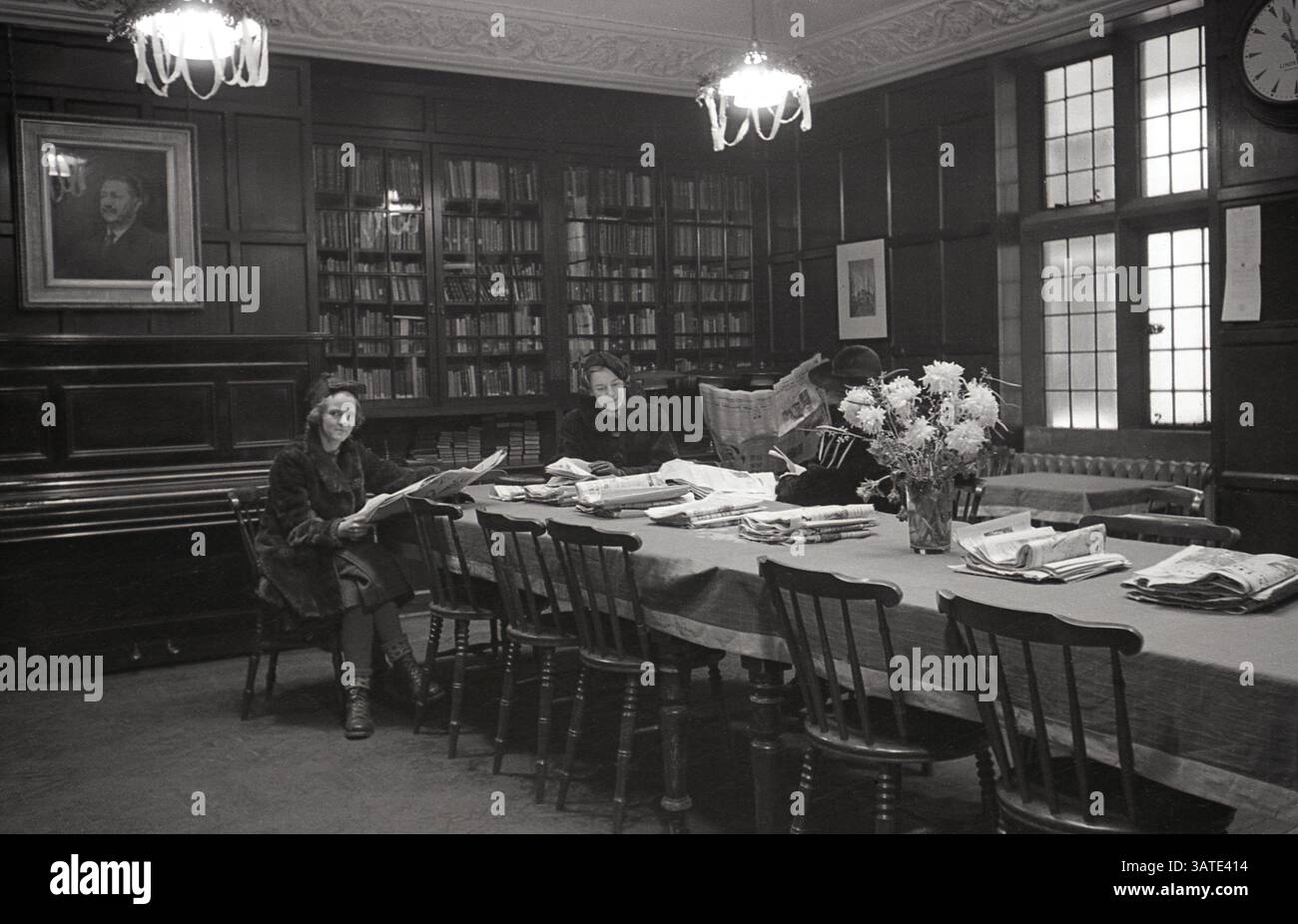 1930, storica, tre signore nell'elegante biblioteca della chiesa svedese di Londra a Harcourt Street, Marylebone, sedute ad un lungo tavolo a leggere giornali. La chiesa svedese, conosciuta anche come la parrocchia svedese di Ulrika Eleonora a Londra, fa parte della "Chiesa di Svezia a bordo" (SKUT). Foto Stock