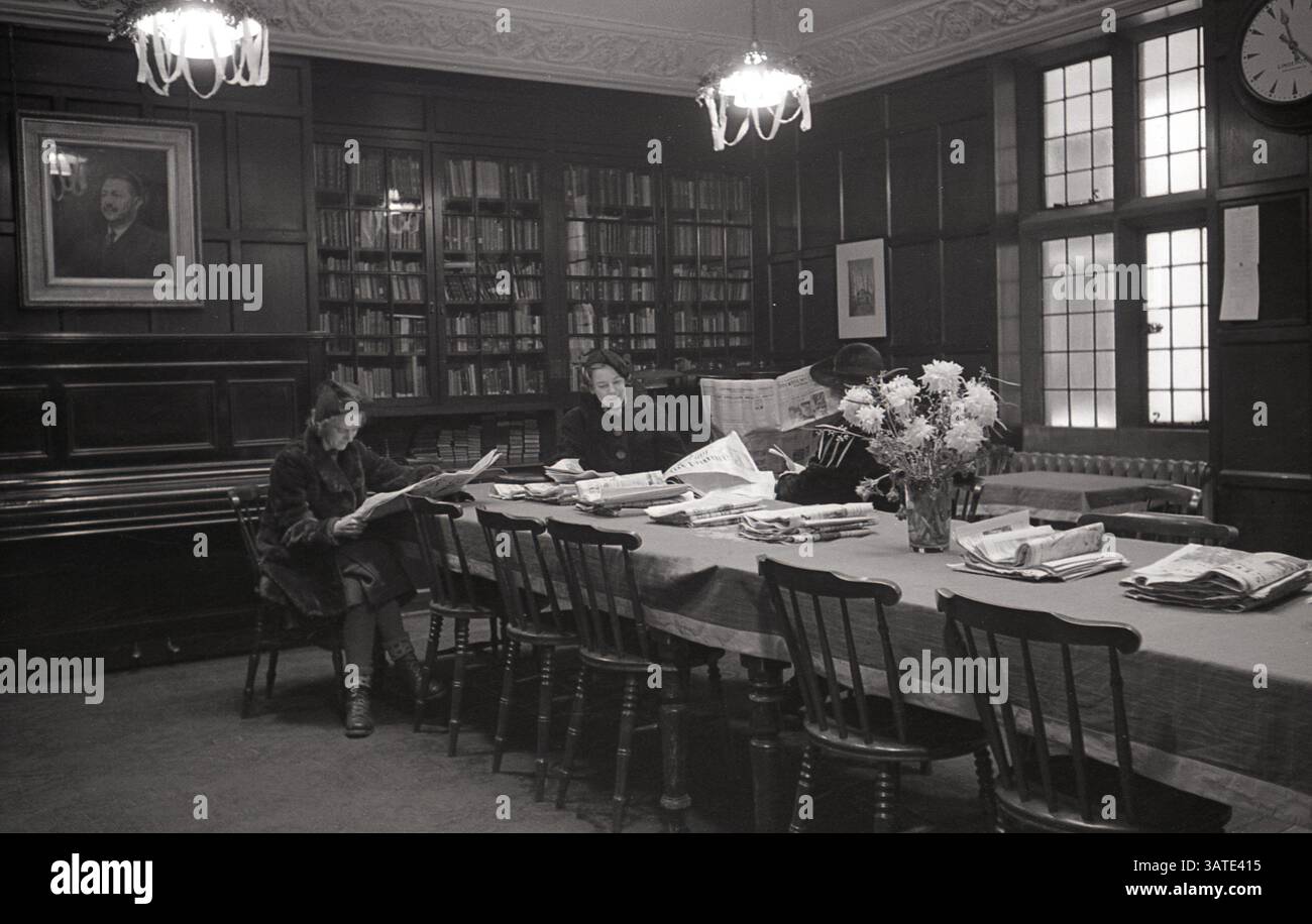 1930, storica, tre signore nell'elegante biblioteca della chiesa svedese di Londra a Harcourt Street, Marylebone, sedute ad un lungo tavolo a leggere giornali. La chiesa svedese, conosciuta anche come la parrocchia svedese di Ulrika Eleonora a Londra, fa parte della "Chiesa di Svezia a bordo" (SKUT). Foto Stock