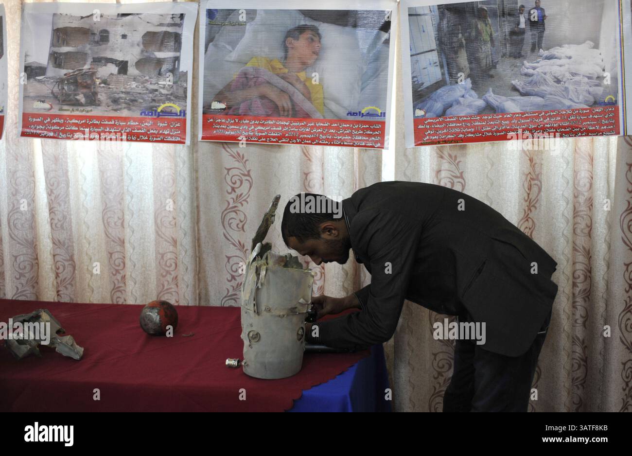6 novembre 2013 - Sana'a, Yemen - Un uomo yemenita guarda pezzi di missili USA usati nello Yemen durante una mostra tenutasi a Sana'a che chiede al governo degli Stati Uniti di fermare i suoi attacchi con droni in questo povero paese. Da quando gli Stati Uniti hanno lanciato il suo primo attacco letale con droni in Yemen nel 2002 fino alla metà del 2013 come parte della sua politica antiterrorismo, il programma si è notevolmente ampliato. I gruppi per i diritti umani hanno criticato la mancanza di trasparenza e gli standard fondamentali del diritto internazionale che inquadrano questa guerra segreta. Lo sciopero dei droni del 92 in Yemen ha causato tra i 680 e i 880 yemeniti uccisi, tra cui 60 civili. ( Foto Stock