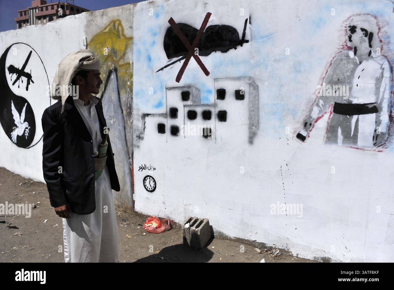 6 novembre 2013 - Sana'a, Yemen - Uno stand yemenita guarda la grafica dipinta sul muro contro i droni statunitensi utilizzati nello Yemen durante una campagna sul muro chiede al governo degli Stati Uniti di fermare i suoi attacchi con i droni in questo paese povero. Da quando gli Stati Uniti hanno lanciato il suo primo attacco letale con droni in Yemen nel 2002 fino alla metà del 2013 come parte della sua politica antiterrorismo, il programma si è notevolmente ampliato. I gruppi per i diritti umani hanno criticato la mancanza di trasparenza e gli standard fondamentali del diritto internazionale che inquadrano questa guerra segreta. Lo sciopero dei droni del 92 in Yemen ha causato tra i 680 e i 880 yemeniti uccisi, tra cui 60 civili. (CR Foto Stock